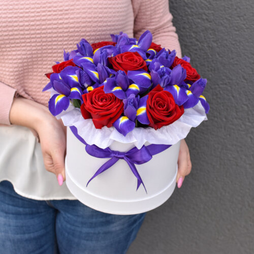 A bouquet containing red roses and blue irises